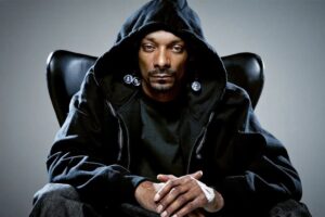 picture of Snoop Dogg wearing a a black hoody, sitting on a black armchair