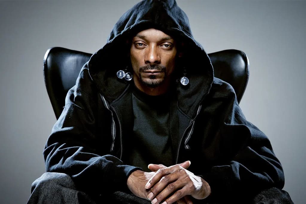 picture of Snoop Dogg wearing a a black hoody, sitting on a black armchair